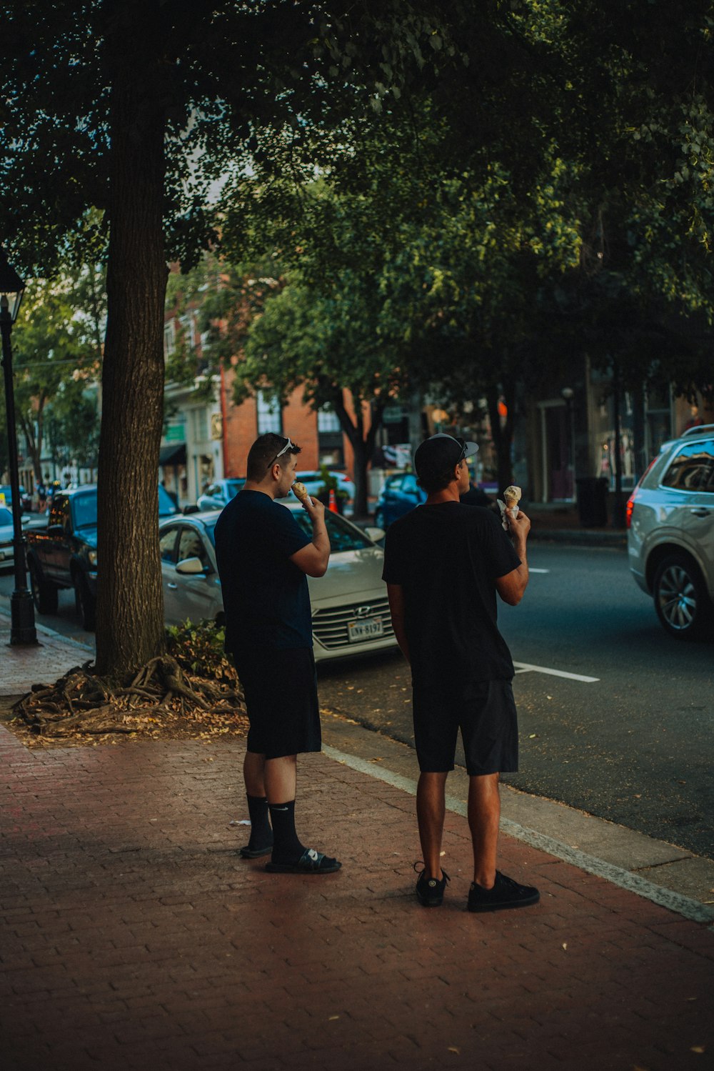 Homme en t-shirt noir et short noir debout sur le trottoir pendant la journée