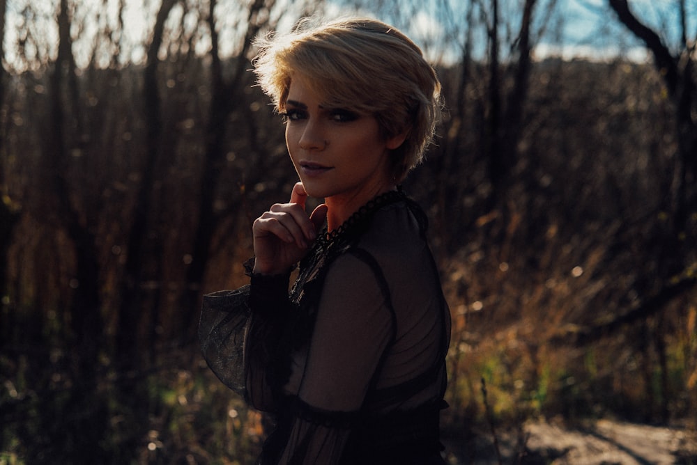 woman in black jacket standing near trees during daytime