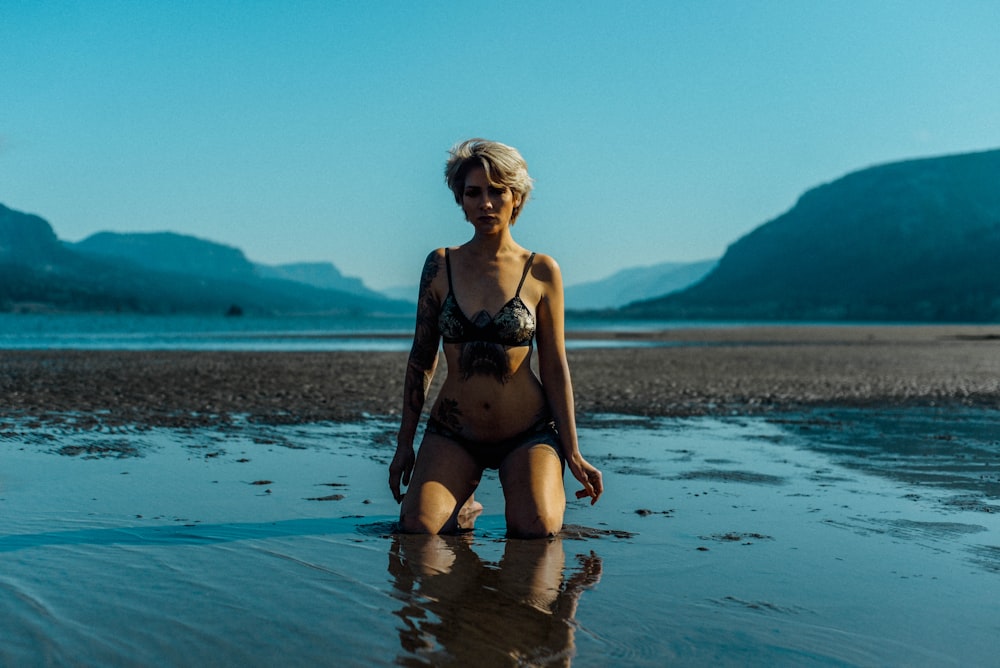 Frau im schwarzen Bikini steht tagsüber auf dem Wasser
