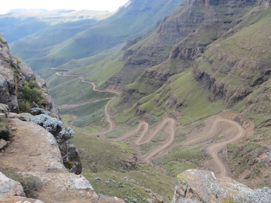 green grass field and mountains during daytime in Sani Pass South Africa