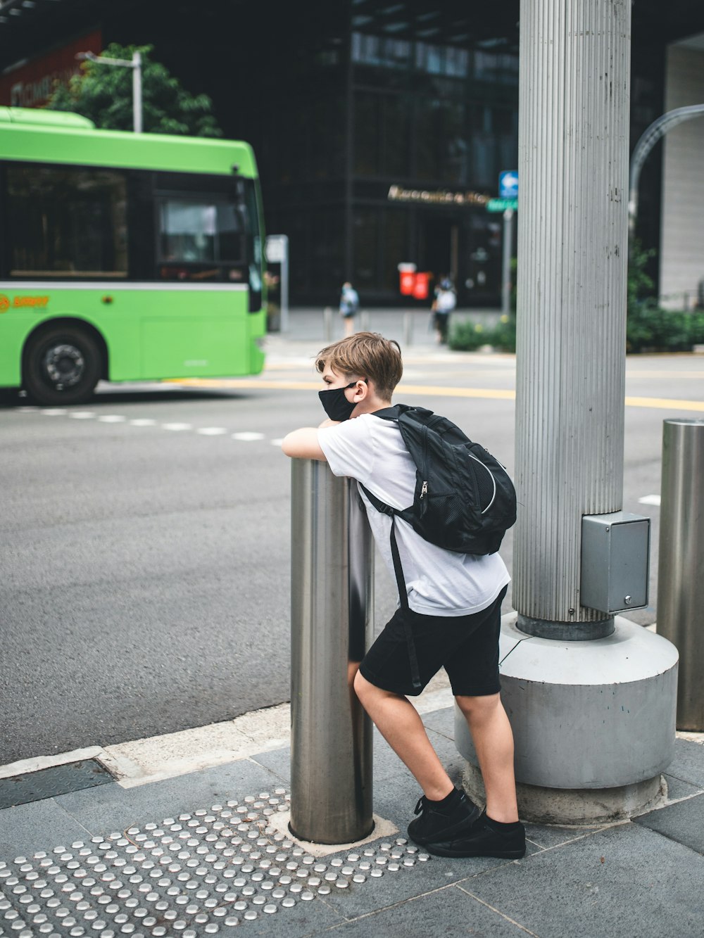 woman in white shirt and black shorts standing on sidewalk during daytime