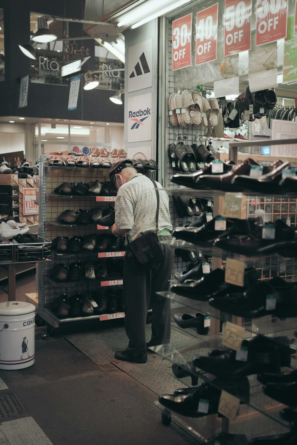 man in white dress shirt and gray pants standing in front of shoes display