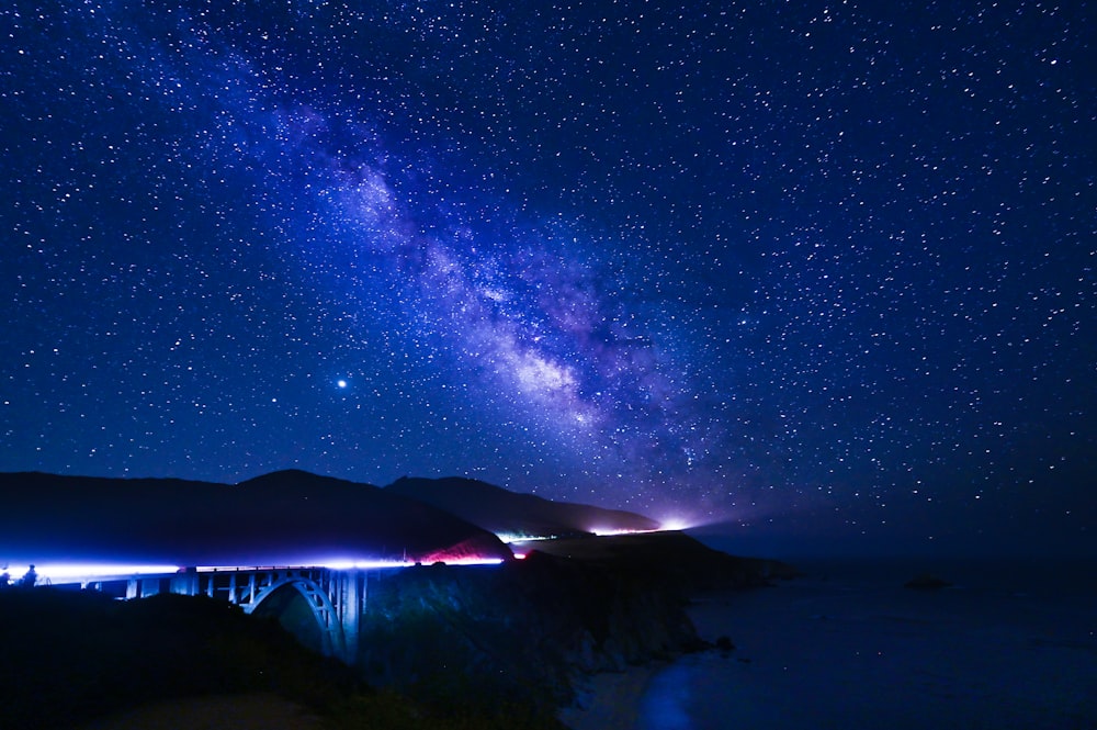 silhouette of mountain under blue sky with stars during night time