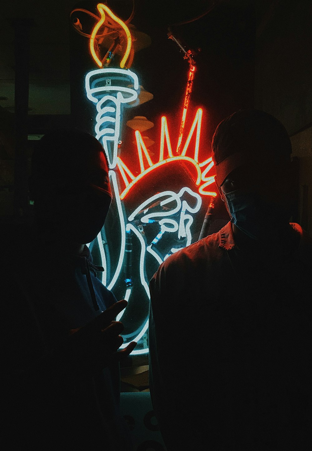 man in black hoodie standing beside red neon light signage