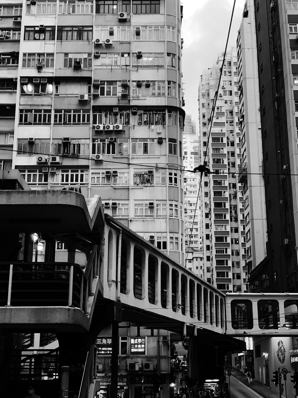 Foto en escala de grises de personas caminando por escaleras cerca de edificios de gran altura