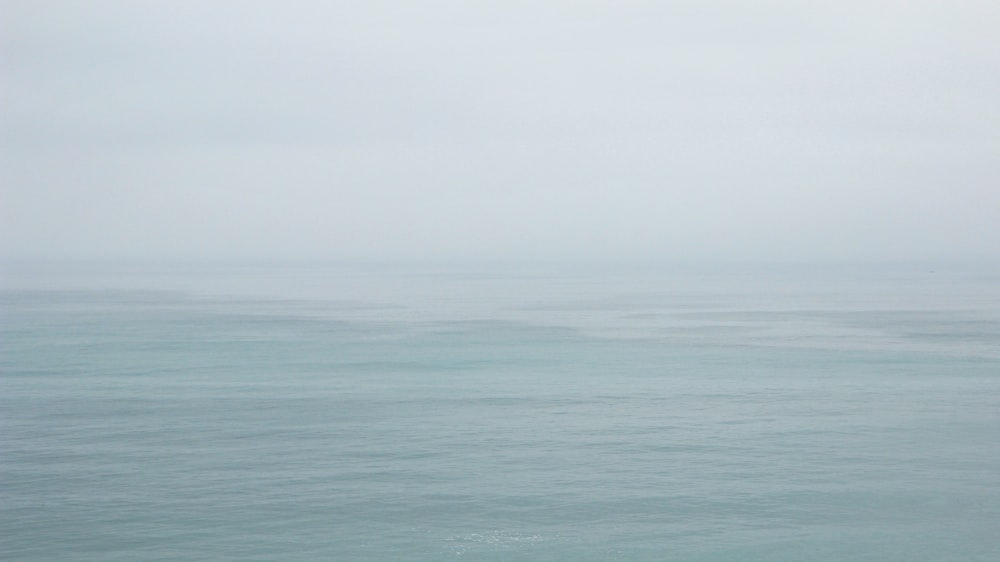 body of water under white sky during daytime