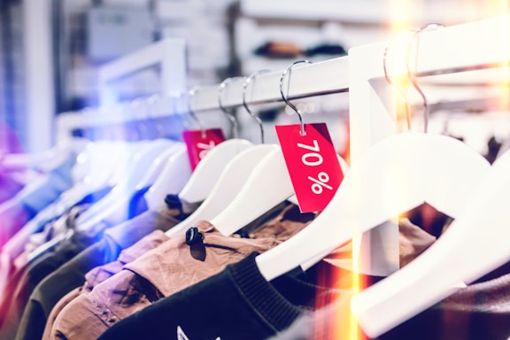 A row of clothing items hanging on white hangers, with several red tags indicating a 70% discount.