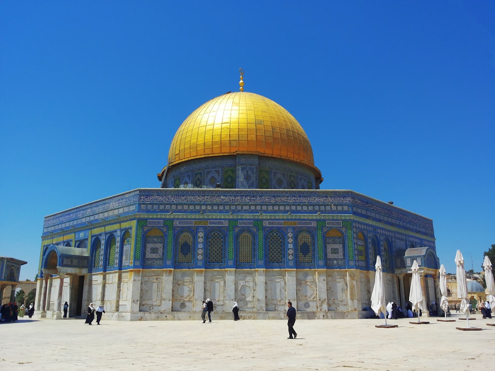 people walking near green and brown dome building under blue sky during daytime