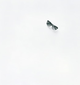 A pair of black sunglasses is placed on a large expanse of plain white surface. The minimalistic composition draws attention to the sunglasses, creating a sense of simplicity and focus.