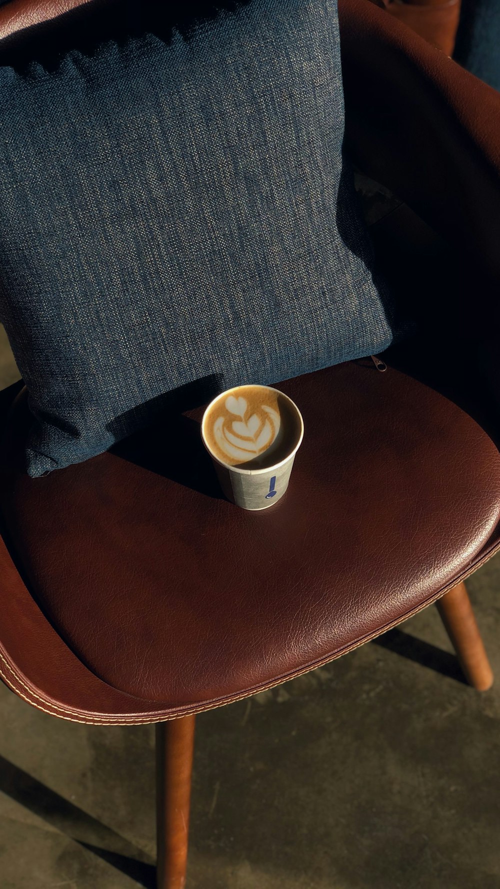 white and brown ceramic mug on brown leather chair