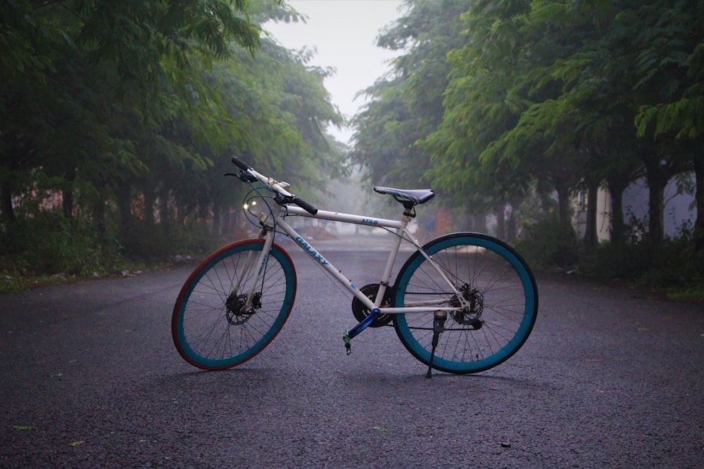 black and white road bike on road near green trees during daytime