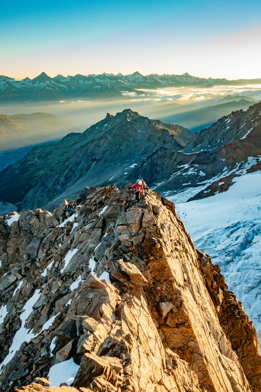 person in red jacket standing on rocky mountain during daytime