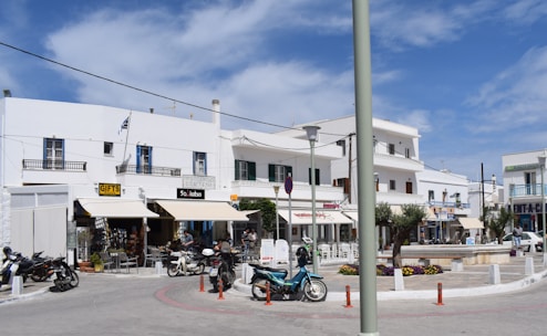 A lively street scene in Ierapetra with tourists exploring on scooters under sunny skies.