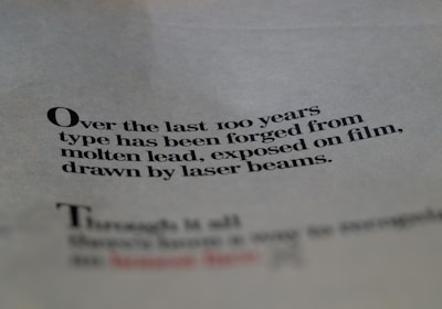 Text printed on paper with a focus on the evolution of typography over the last century, mentioning molten lead and laser beams.