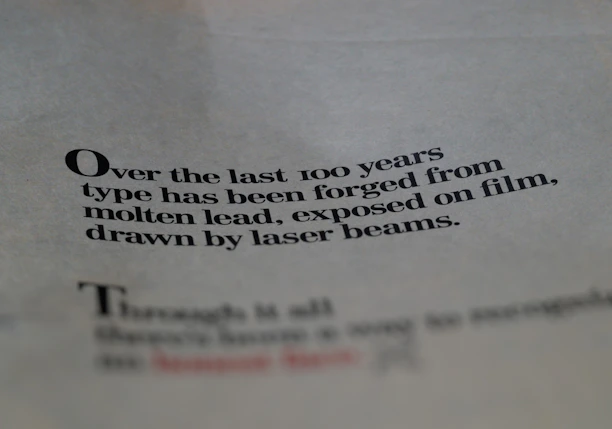 Text printed on paper with a focus on the evolution of typography over the last century, mentioning molten lead and laser beams.