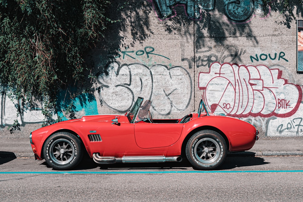 red ferrari california parked beside wall with graffiti