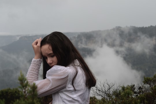 woman in white sweater covering her face with her hands in Blue Mountains Australia