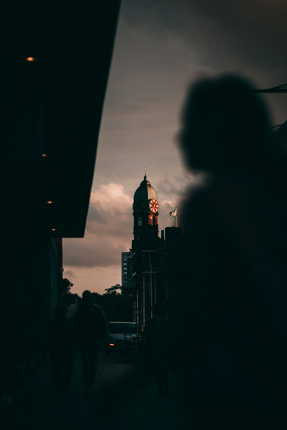 silhouette of woman standing near high rise building during night time