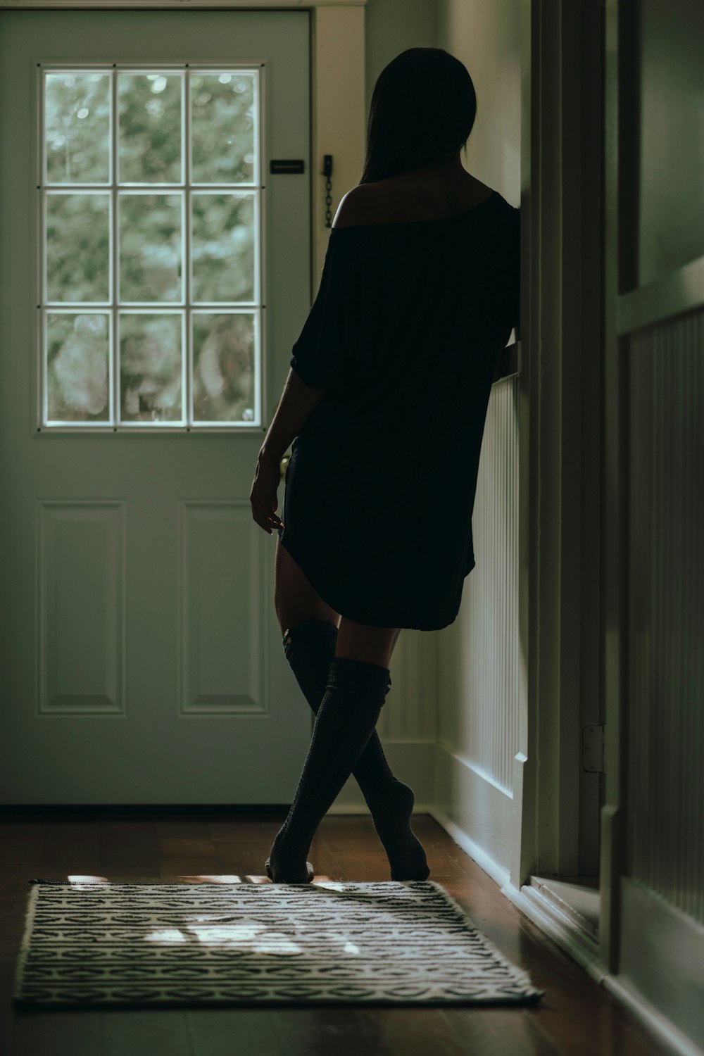 woman in black dress standing near white wooden door