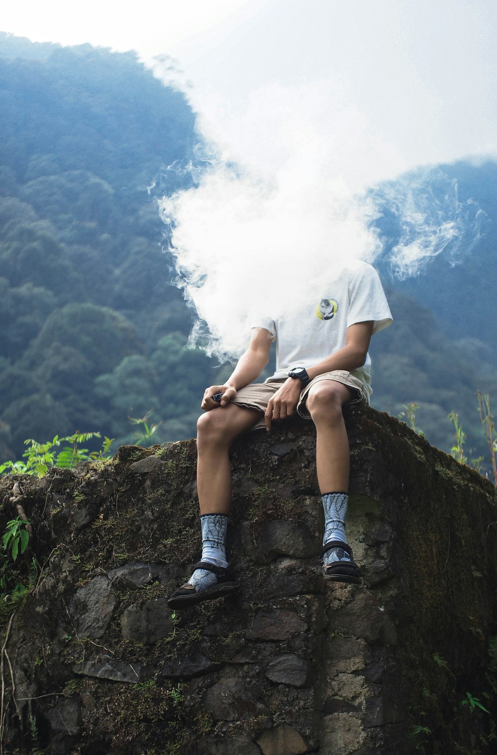 person in gray shorts sitting on rock during daytime