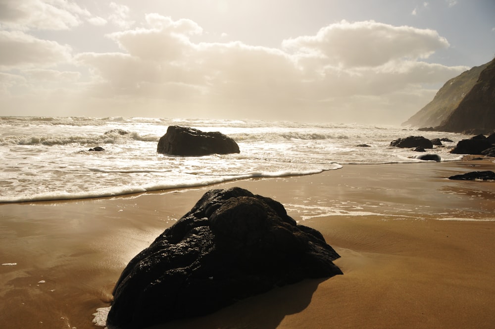 black rock formation on sea shore during daytime