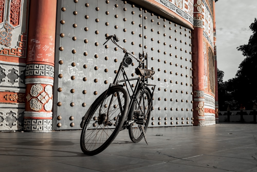 black city bike parked beside red and white wall