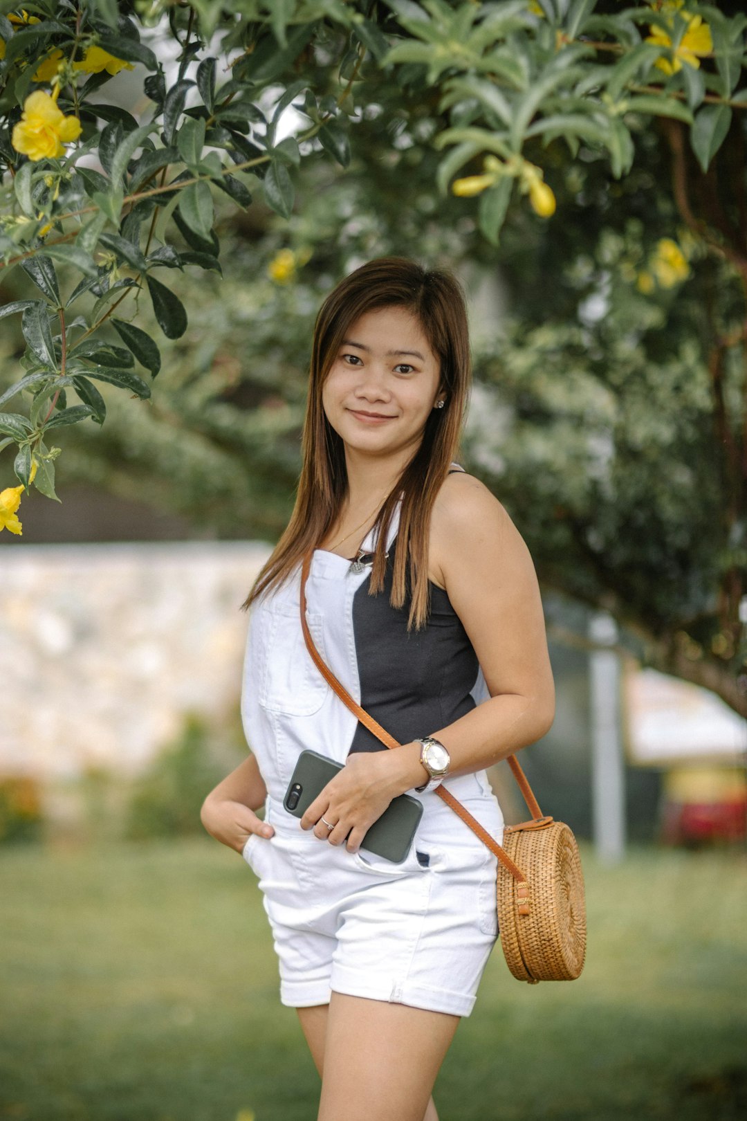 woman in white sleeveless dress holding brown leather sling bag