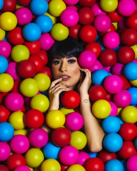 woman in white tank top with assorted color balloons on her face