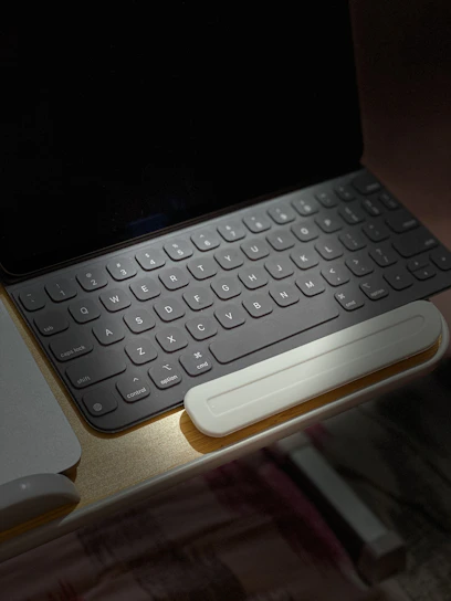 A sleek proprioceptive keyboard with soft green backlighting on a clean white desk.