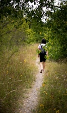 woman in black dress walking on green grass during daytime