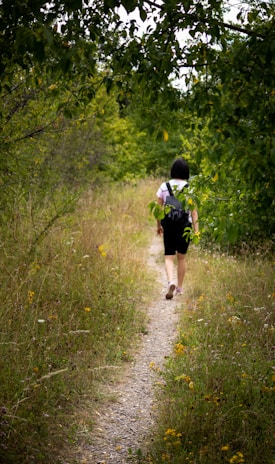 woman in black dress walking on green grass during daytime