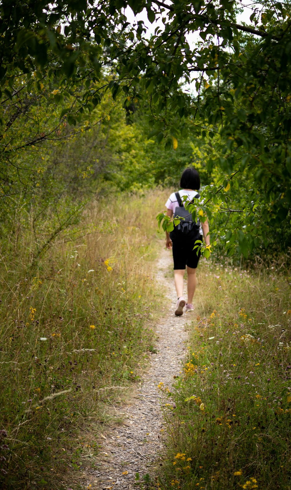 woman in black dress walking on green grass during daytime