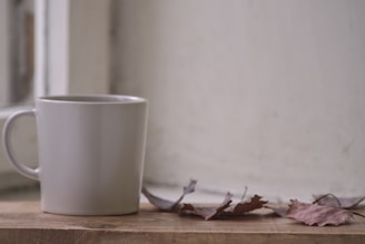 Close-up of a minimalist ivory mug resting on a soft beige linen cloth with natural morning light filtering in.