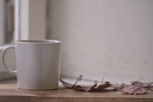 Close-up of a minimalist ivory mug resting on a soft beige linen cloth with natural morning light filtering in.