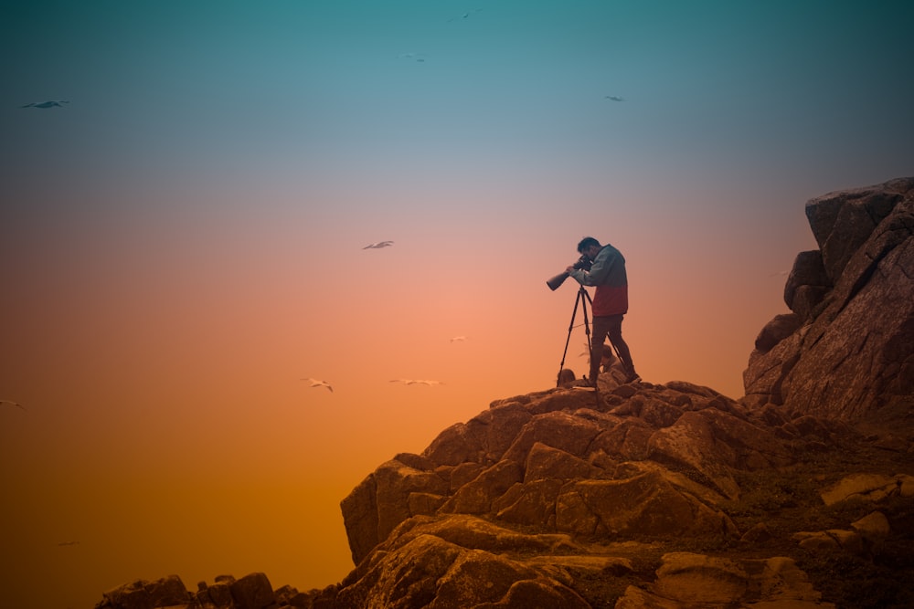 man in black jacket and black pants standing on brown rock formation during daytime