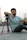 man in teal crew neck t-shirt sitting on black and gray tripod