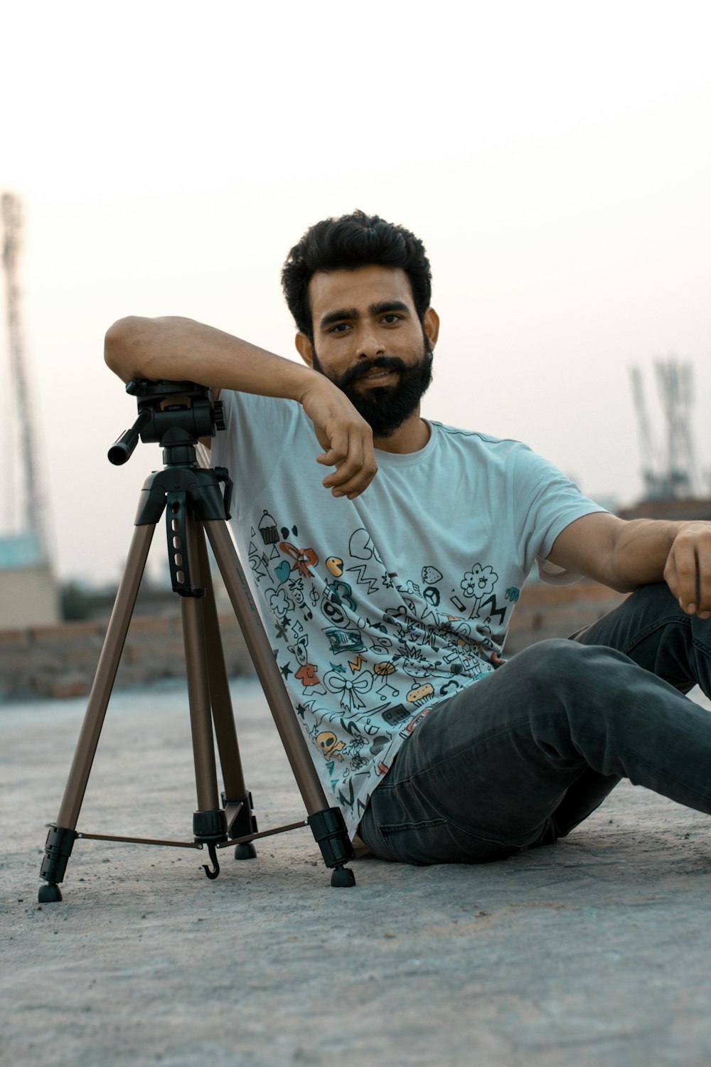 man in teal crew neck t-shirt sitting on black and gray tripod