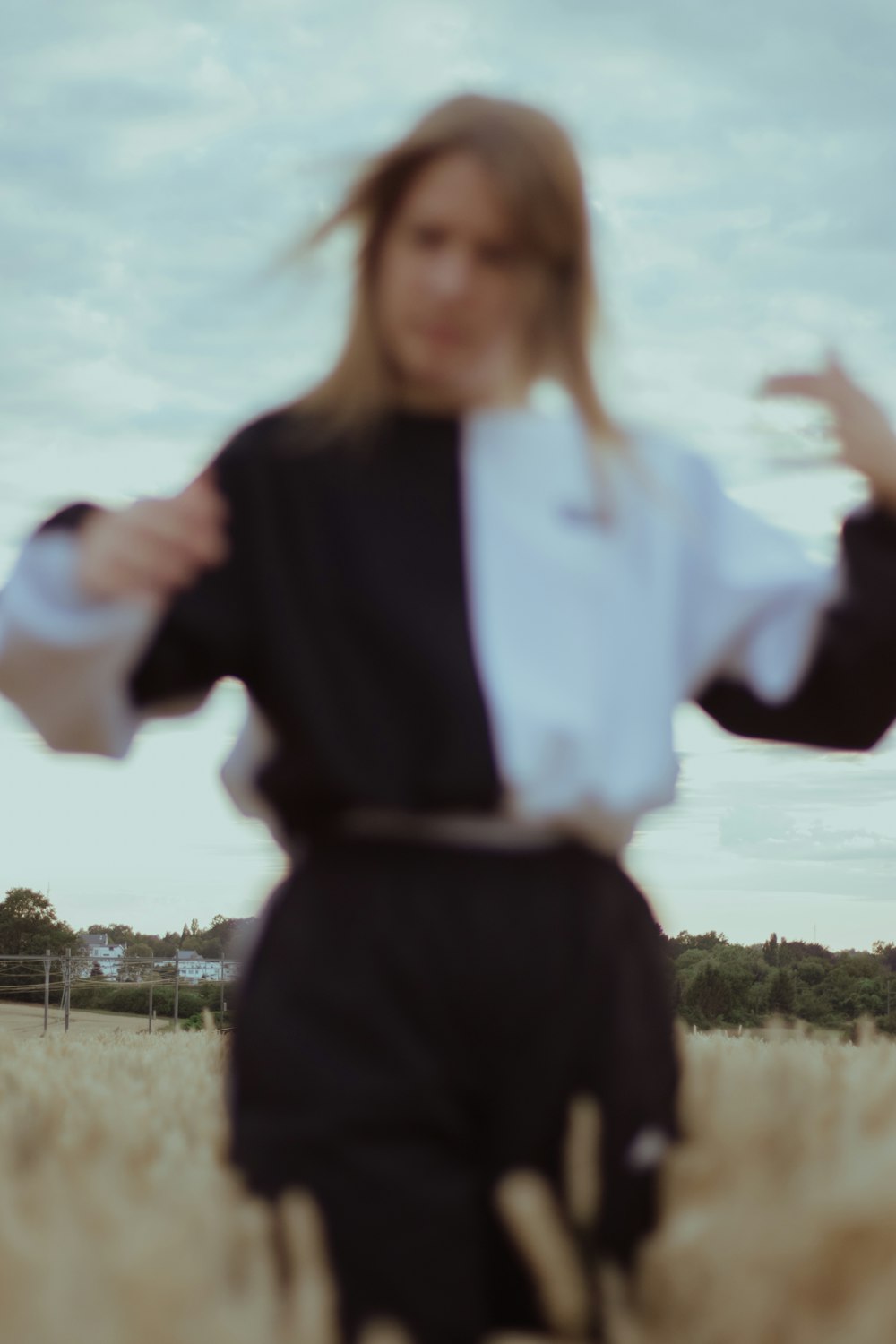 woman in blue and white long sleeve shirt and black pants standing on green grass field