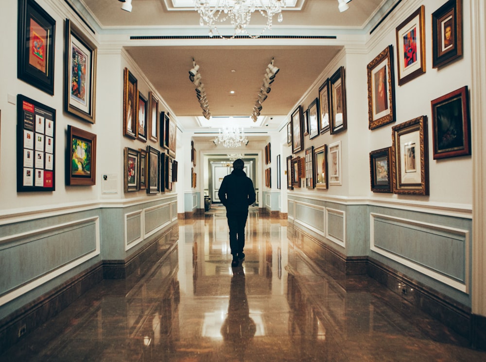 man in black jacket walking on brown wooden parquet floor