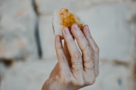 A hand holding a polished amethyst stone against a soft natural background.