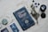 A dark blue book titled 'Moon Magic' lies on a textured fabric surface, accompanied by various mystical items such as gemstones, a small branch of herbs, and a pendant necklace. There are also cards with mystical imagery and a decorative stone nearby, conveying a sense of the occult and spirituality.
