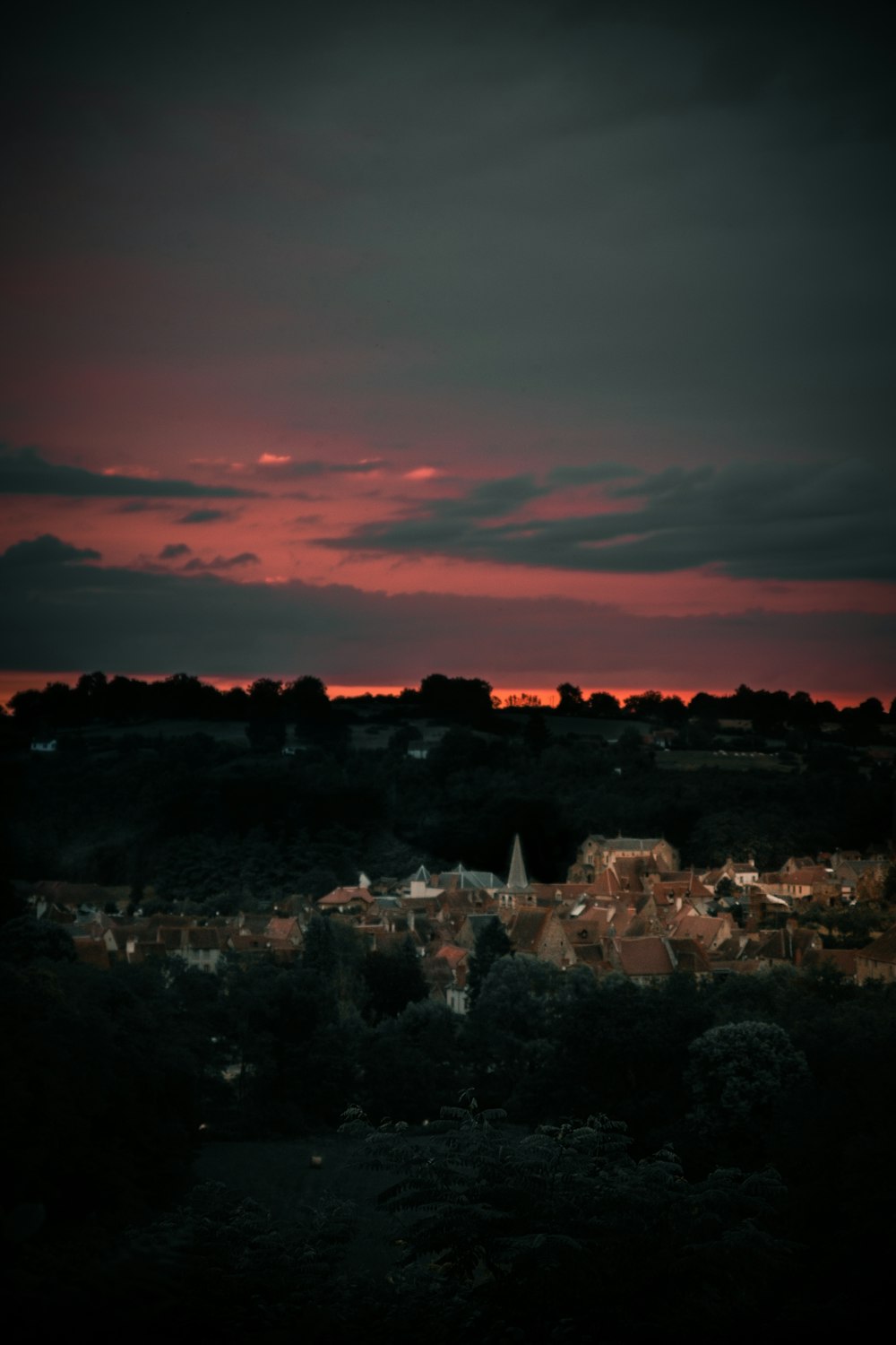 city with high rise buildings under orange and gray skies