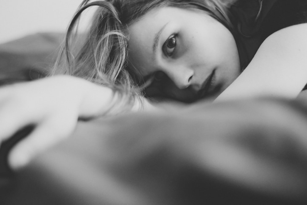 grayscale photo of woman lying on bed