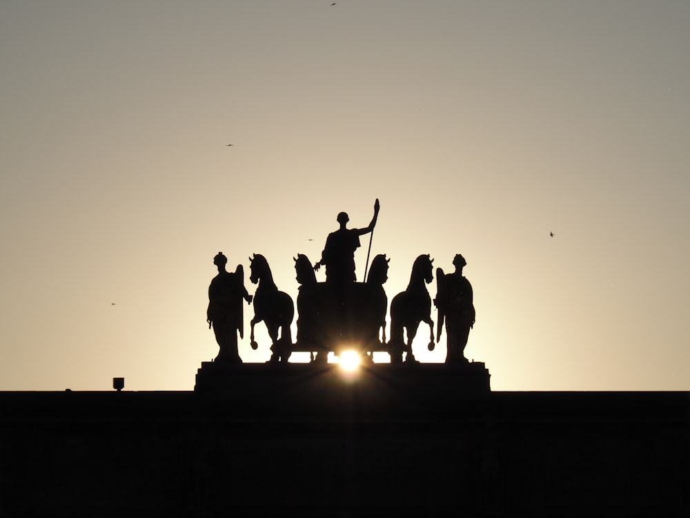 silhouette of people jumping on top of building during sunset