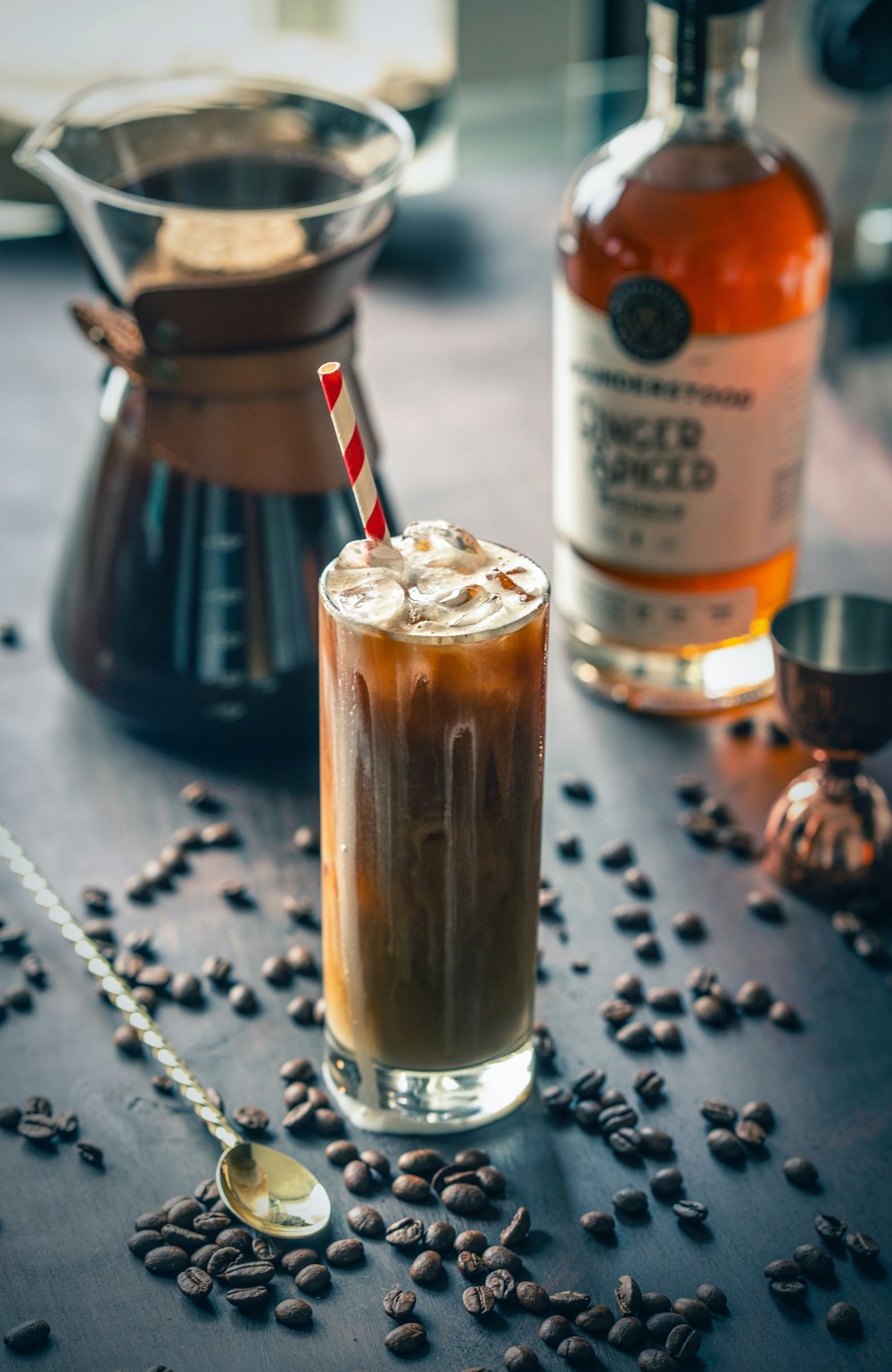 clear drinking glass with brown liquid and ice cubes on brown wooden table