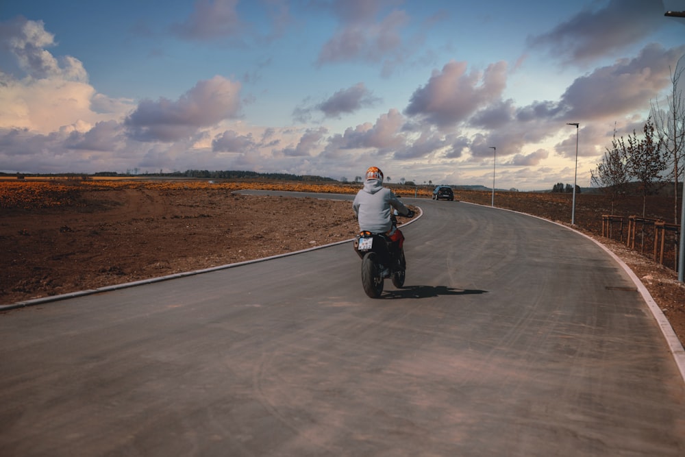 man in white shirt riding motorcycle on road during daytime