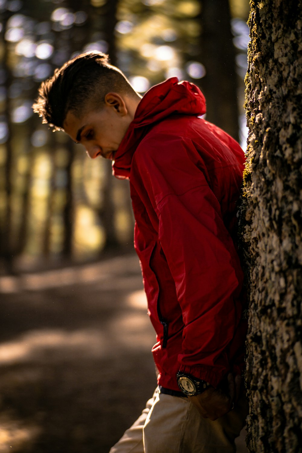 boy in red hoodie leaning on tree