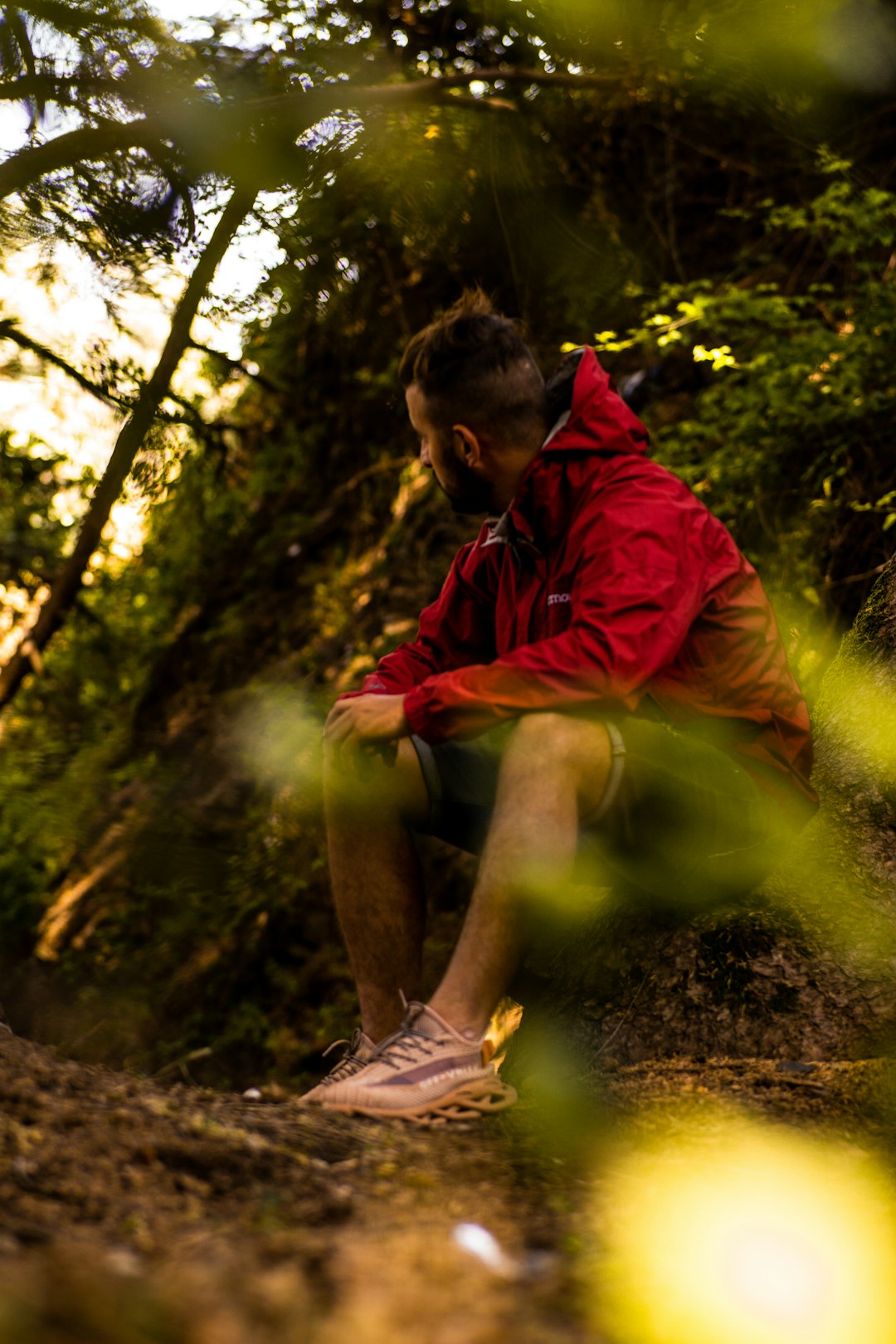 man in red hoodie sitting on brown rock