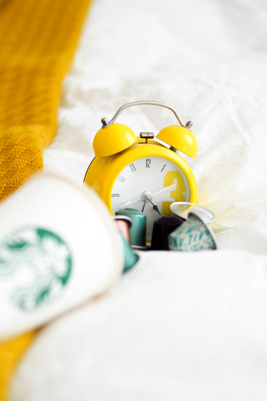 yellow alarm clock beside white ceramic mug