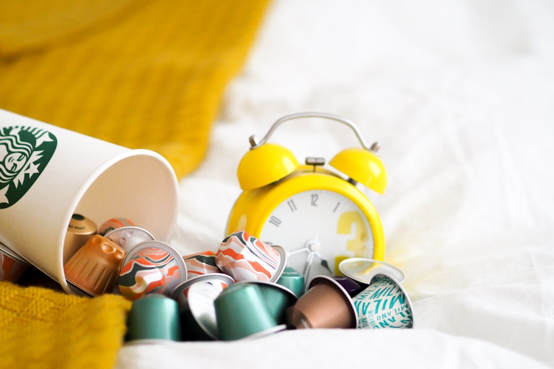 yellow alarm clock beside green and white ceramic mugs